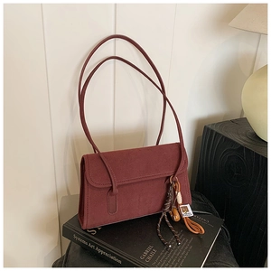 Detail view of a vintage frosted burgundy shoulder bag resting on artistic books