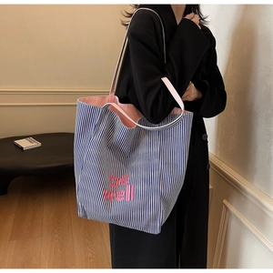 Detailansicht der blau gestreiften Canvas-Tasche mit pinkem Aufdruck am Model
