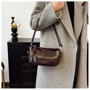 Détail du sac sous le bras Ceneka marron foncé porté avec un manteau gris moderne