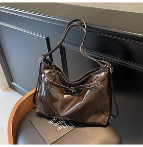 Detailed close-up of a dark brown patent leather tote bag with white contrast stitching