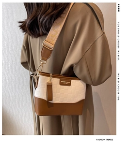 Detail of checkered texture and wide strap on a brown leather crossbody hobo bag