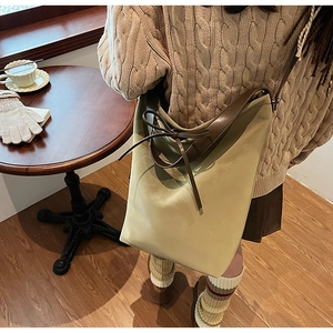 Detail of casual shoulder bag featuring a decorative bow and contrasting brown leather strap