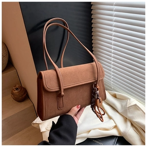 Detail of brown vintage matte leather shoulder bag featuring twin straps and side ring charm