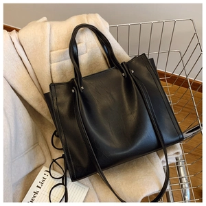 Detail shot of black faux leather tote bag with silver hardware inside a shopping cart