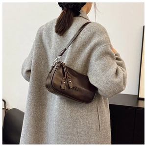 Détail du sac sous l'aisselle en cuir marron foncé avec texture et rivets métal