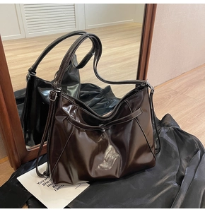 Detail of dark brown glossy leather tote bag with elegant white contrast stitching