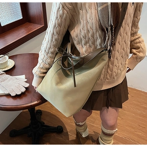 Détail d'un grand sac cabas avec nœud marron et bandoulière en cuir porté par un mannequin