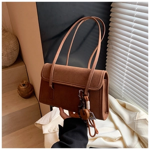 Macro detail of brown frosted suede handbag featuring vintage wooden ring tassel charm