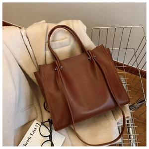Detail view of a brown faux leather tote bag with silver rivets in a shopping cart