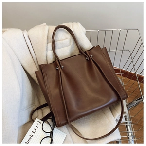 Brown faux leather tote bag with silver studs placed in a metal shopping cart