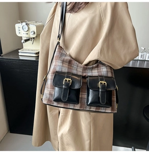Close-up of retro plaid shoulder bag with double black leather pockets and gold metal buckles