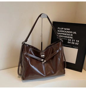 Detailed view of dark brown leather tote bag featuring silver twist lock and white stitching
