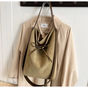 Detail view of khaki suede tote bag with decorative bow and dark brown wide shoulder strap