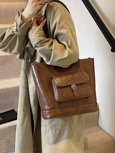 Retro brown large capacity tote bag with buckle pocket shown on a model's shoulder
