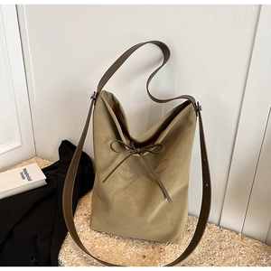 Detail of khaki hobo shoulder bag featuring leather strap and delicate bow texture print