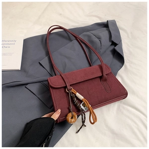 Macro detail of wine red frosted suede underarm bag with decorative donut charm
