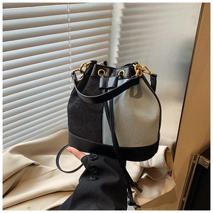 Detail of contrast bucket bag showing canvas texture with leather trim and gold hardware