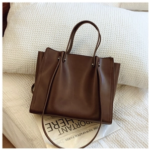 Detail shot of a dark brown large capacity tote bag with silver rivets and leather texture