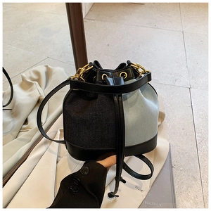 Detail of color-block drawstring bucket bag with premium leather trim and gold hardware