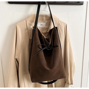 Detailed view of dark brown suede tote bag with a decorative black leather bow accent