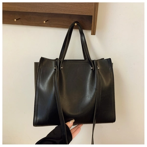Detail view of reinforced handles and stitching on this large matte black tote bag