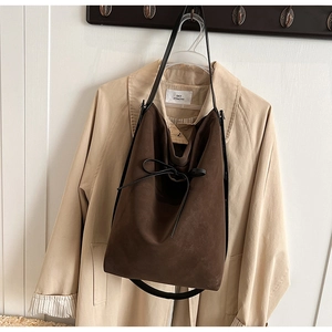 Detail view of dark brown suede bucket bag featuring elegant decorative black bow knot