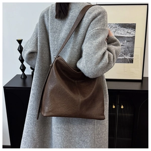 Retro brown textured leather tote bag shown on model with grey wool coat in chic interior