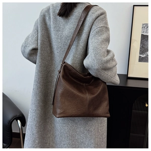 Detailed view of deep brown vintage bucket bag with pleated leather texture on model