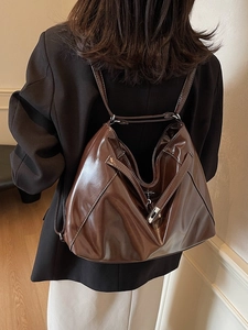 Dark brown glossy patent leather tote bag with geometric fold design and silver clasp