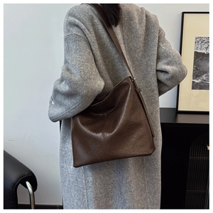 Detail view of the brown vintage leather tote bag worn with a long grey wool coat