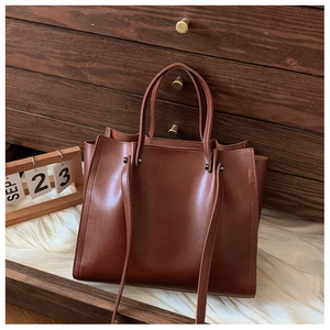 Close-up of caramel brown minimalist tote bag with dual straps and smooth faux leather finish