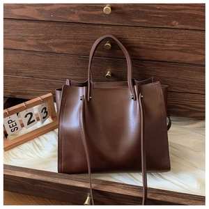 Macro view of deep brown matte leather tote bag with stylish metal rivet details