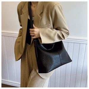 Detail of black large capacity leather tote bag with adjustable strap and vertical stitching