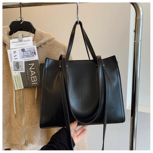 Detailed close-up of a black textured PU leather tote bag with silver metal hardware