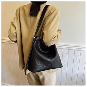 Detail of vintage black litchi grain leather hobo bag worn on shoulder by a model