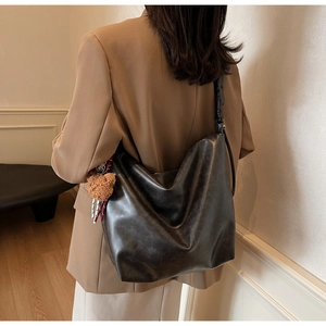 Detail of soft black leather hobo bag featuring a cute brown plush bear charm accessory