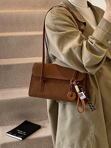 Vintage matte brown shoulder bag for women styled with a khaki trench coat on stairs