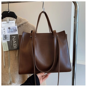 Detail of dark brown leather tote bag showing fine matte texture and durable shoulder strap
