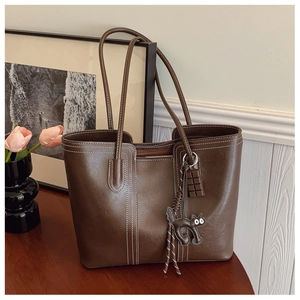 Detail of dark brown leather tote with white contrast stitching and cute charms