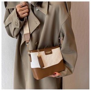 Detail of color-block crossbody bag with wide embroidered strap on khaki trench coat