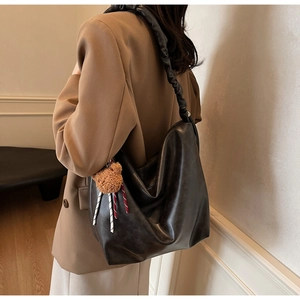 Detail of soft black faux leather tote bag with gathered strap and brown bear charm