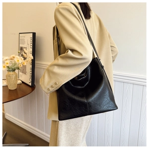 Side view of a vintage black tote bag with pleated texture and thin shoulder strap