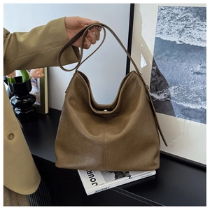 Detail of soft leather texture and adjustable strap on dark brown bucket bag