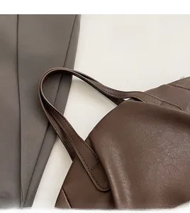 Detail of dark brown leather handbag handle with durable stitching and premium grain texture
