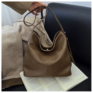 Flat lay of a vintage brown leather bucket bag on an open book with professional attire