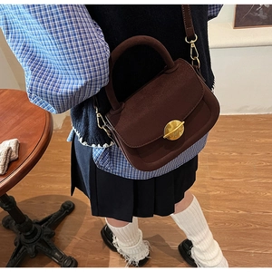Close-up of retro dark brown matte leather saddle bag with gold circular metal buckle