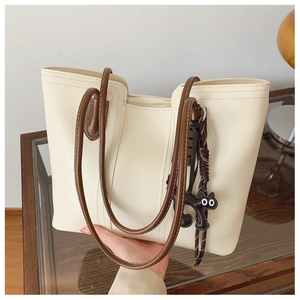 Detail of cream tote bag with brown handles and a cute black cat leather pendant