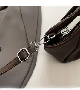 Detail of silver detachable metal hook and zipper on dark brown PU leather bag
