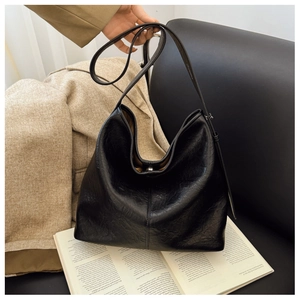 Close-up of black retro bucket bag with wrinkled leather texture on an open book