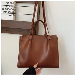 Macro view of vintage brown tote bag texture with metal rivets and sturdy handle detail